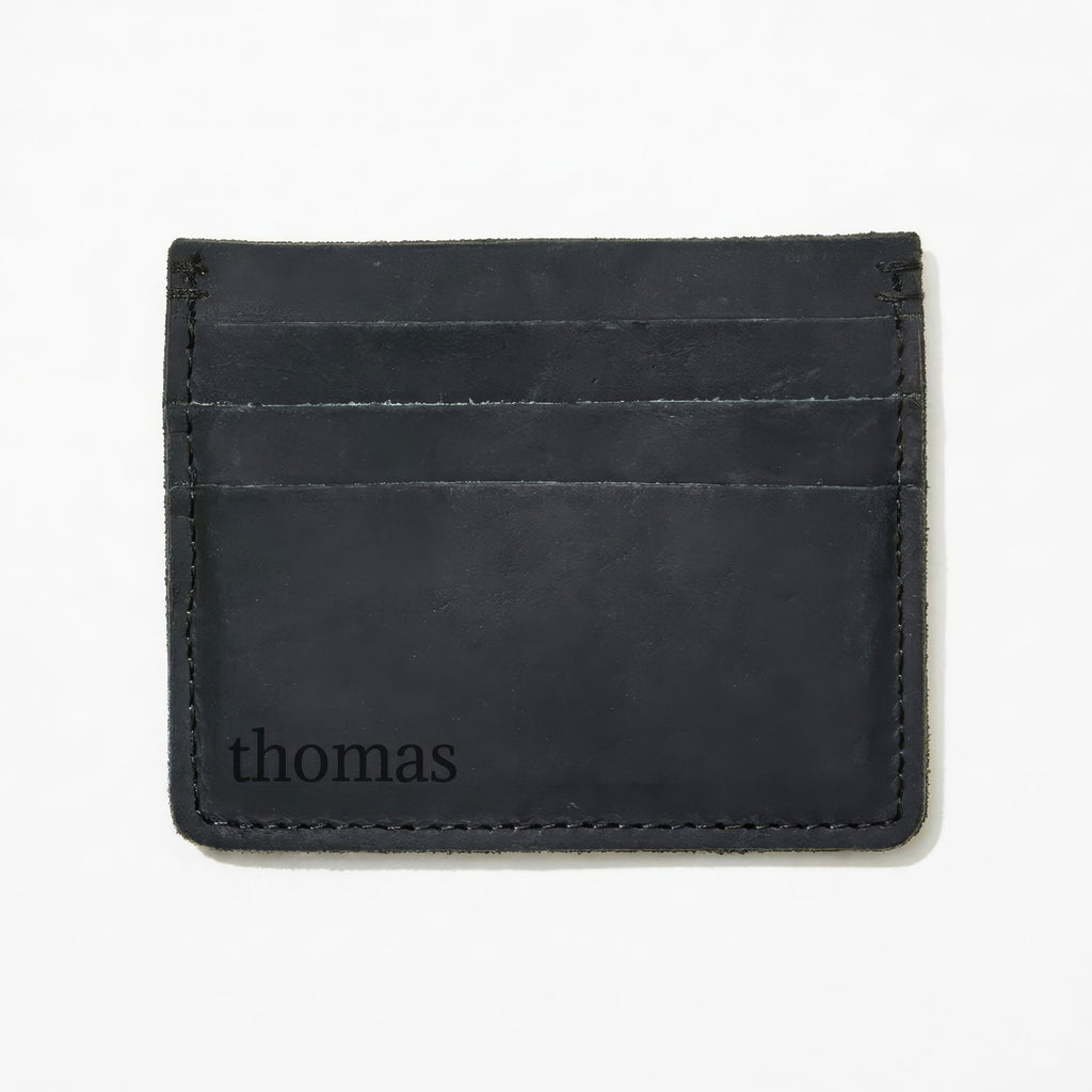 Black leather cardholder with 'thomas' monogram sitting on a white background