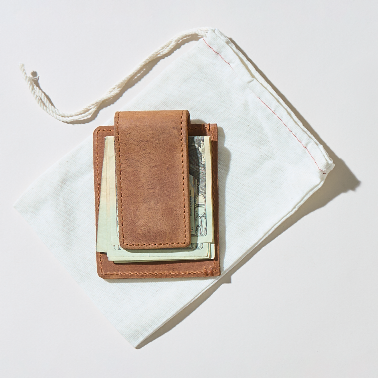 Brown leather money clip with cash on a white background