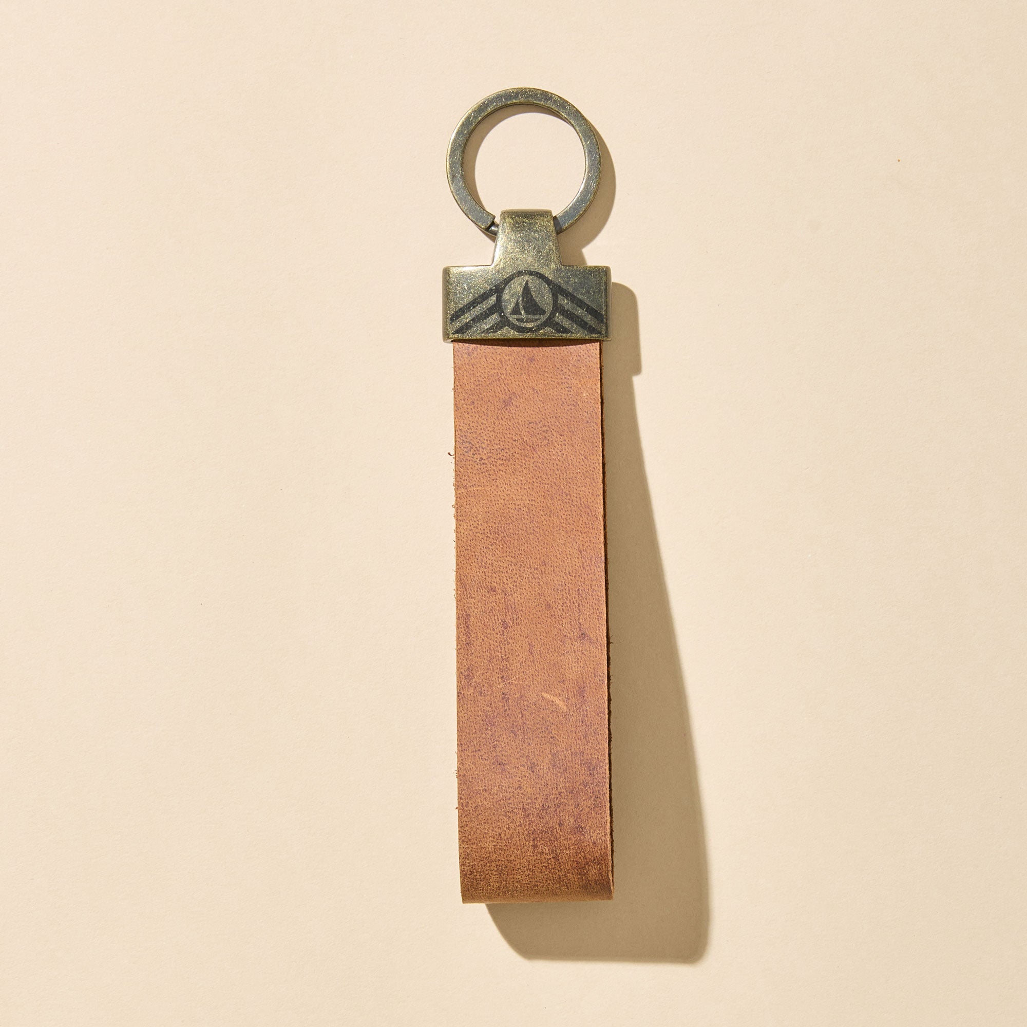 Brown leather keychain with metal ring on a beige background