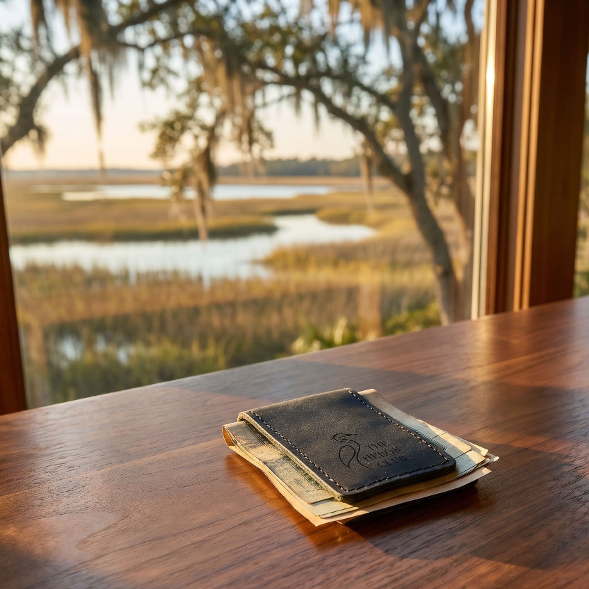 Leather money clip wallet with money on a wooden table with a scenic view outside