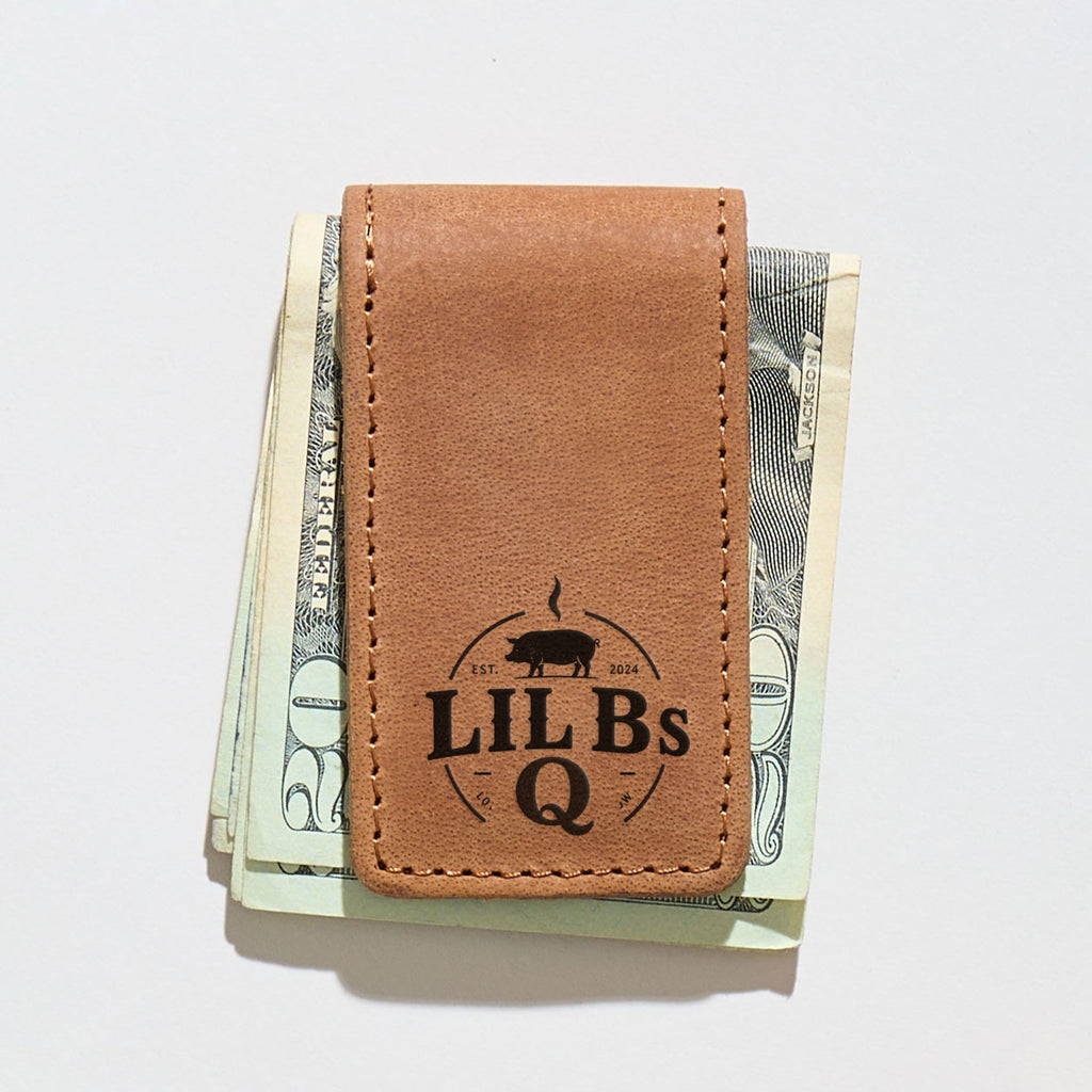 Brown leather money clip with 'LIL BS Q' branding clipped on a stack of US dollars.