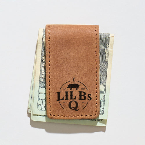 Brown leather money clip with 'LIL BS Q' branding clipped on a stack of US dollars.