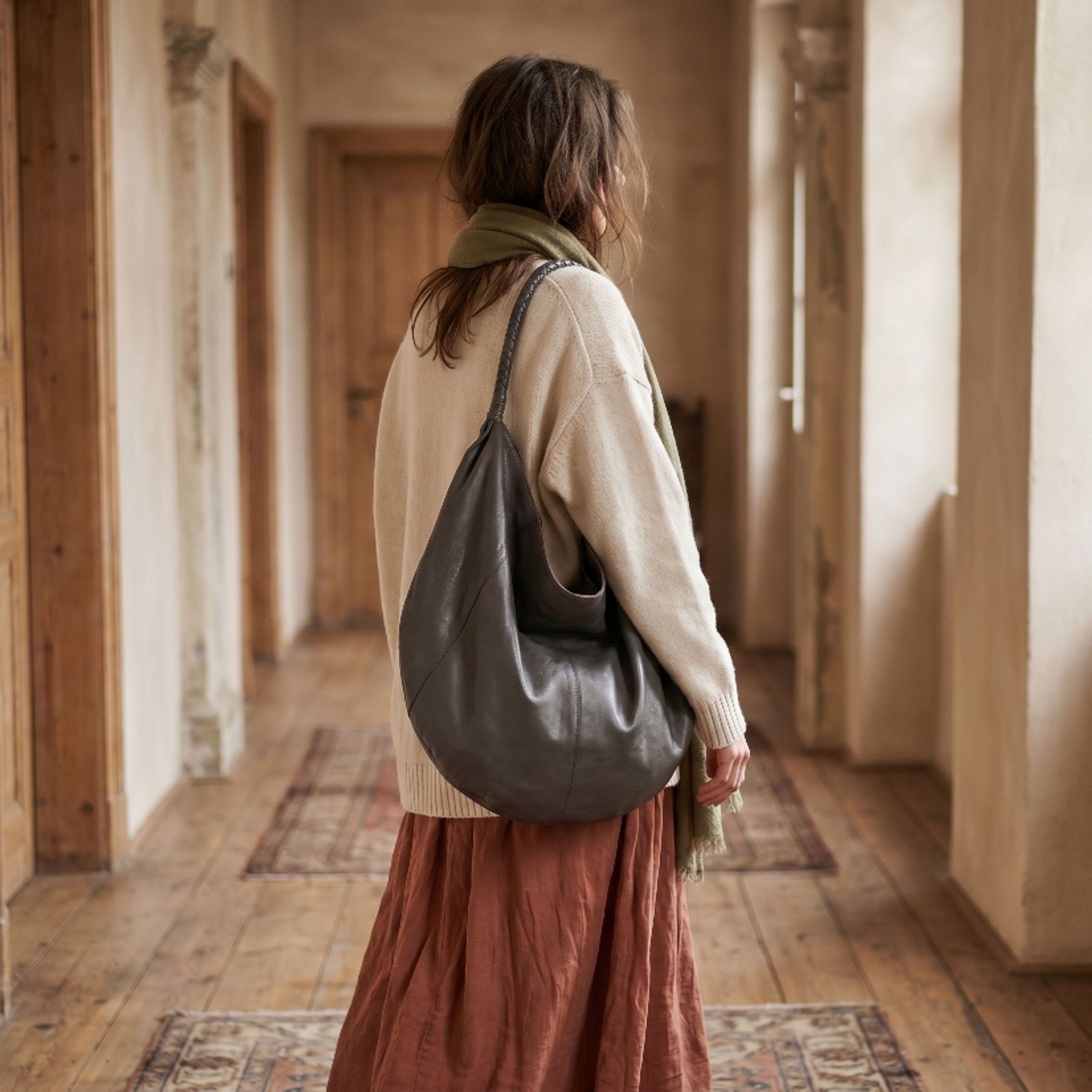 Woman walking down a hallway with a large leather bag